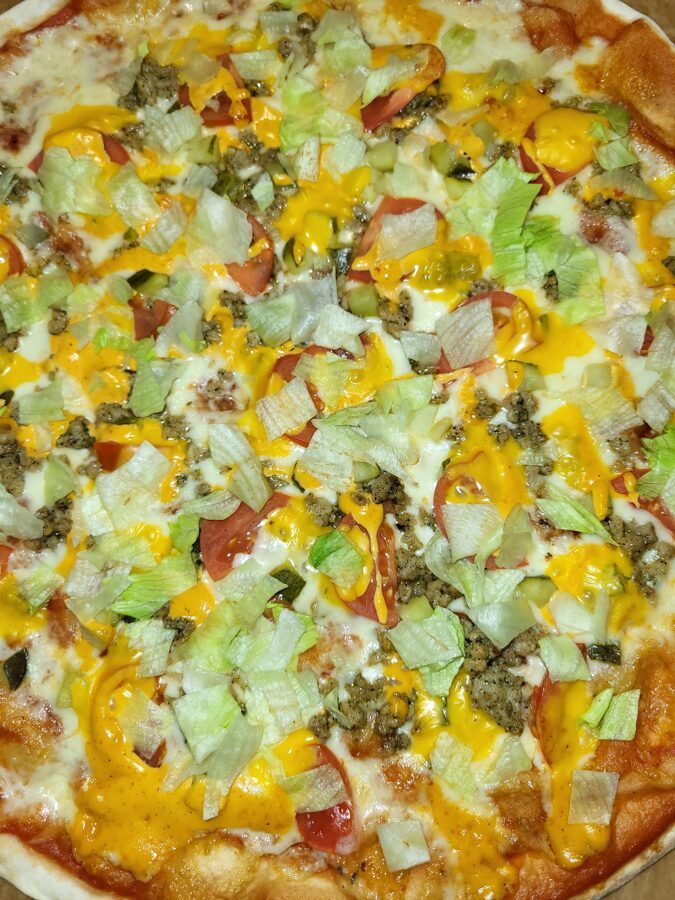 Burger pizza - tomato sauce, cheese, pork minced meat, marinanted cucumber, tomatoes, cheddar cheese, sweet pepper sauce, iceberg lettuce