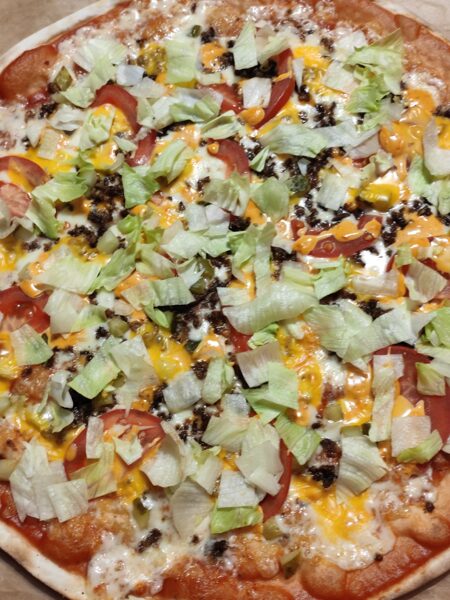 Vegetarian burger pizza tomato sauce, cheese, ground soybeans, pickled cucumber, tomatoes, cheddar cheese, sweet pepper sauce, iceberg lettuce
